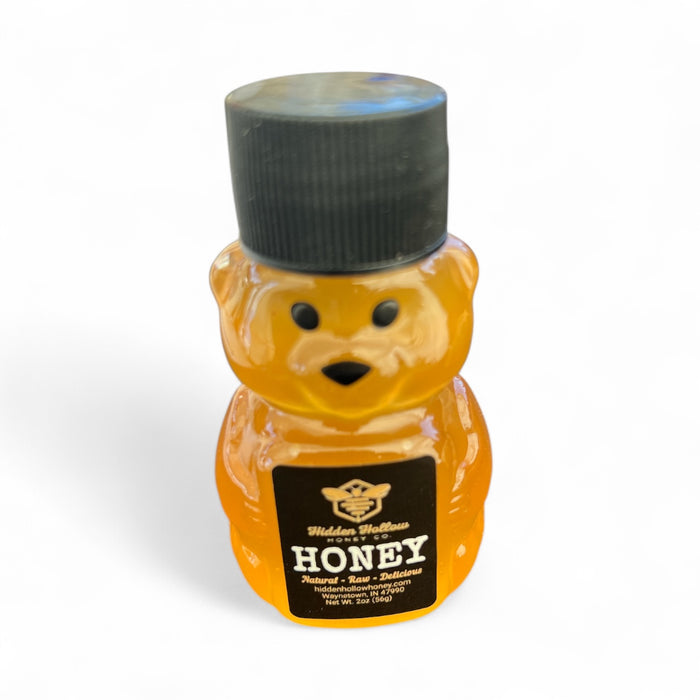 Bear-shaped honey bottle with black cap on a white background
