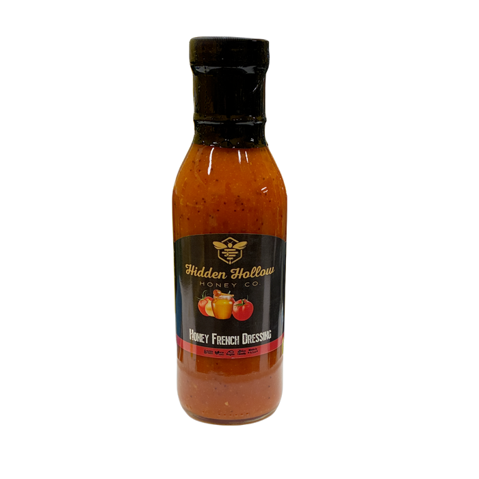 A bottle of Hidden Hollow Honey Co. Honey French Dressing with a black cap and a black label featuring gold lettering and fruit illustrations, set against a plain white background.