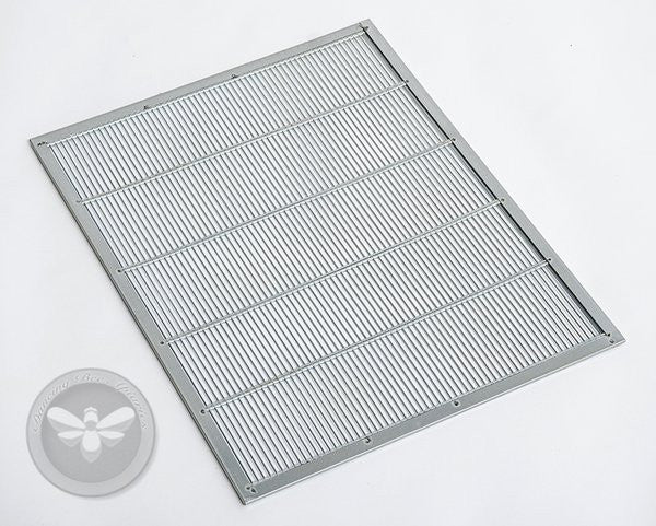 A metal queen excluder with a grid-like pattern used in beekeeping to prevent the queen from entering honey supers.